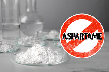 Prohibition sign with word Aspartame symbolizing restriction on use of sugar substitute. Artificial sweetener in Petri dishes on gray table
