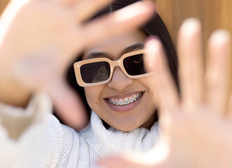 Native American young woman wearing trendy sunglasses doing frame using hands