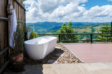 Fototapeta na wymiar bathtub looking out over the mountains of Chiang Rai Northern Thailand during vacation. Outdoor bathroom, bathtub during sunset Doi Chang Mountain