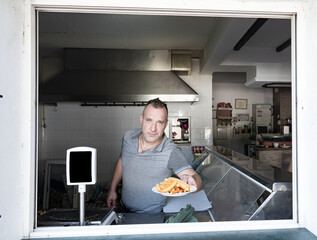 Trabajador de la hostelería o una tienda de alimentación, entregando una ración de fritos. Churrero gaditano vendiendo los churros.