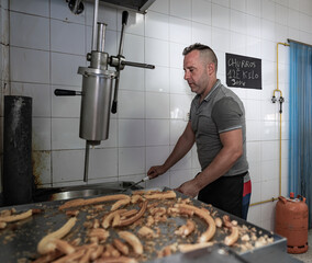 Cocinero friendo masa con dos palos de Churrero para hacer los churros. Los churros son un dulce frito tradicional español.