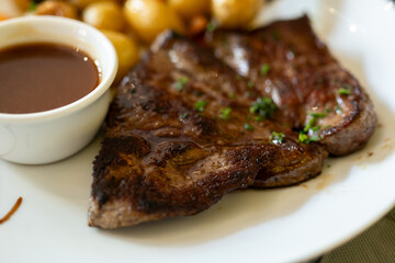 Dish in old bistro in Limoges, France, Limousin cattle beef steak served with oven baked potatos, vegetables and served with light broth or gravy