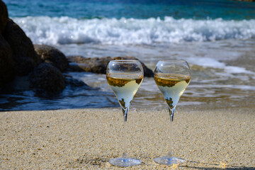 Fototapeta na wymiar Summer time in Provence, two glasses of cold champagne cremant sparkling wine on sandy beach near Saint-Tropez in sunny day, Var department, France
