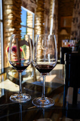 Tasting of red dry wine in Chateauneuf-du-Pape wine making village in France with green vineyards on large pebbles galets and sandstone clay soil