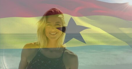Animation of waving flag of ghana over smiling caucasian woman standing against sea at beach - Powered by Adobe