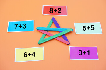 Paper cards with numbers addition, plus for teaching Maths subject. DIY colorful used ice cream sticks in star shape. Concept, teaching aids, Educational number game.         