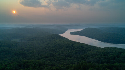 An aerial view of Esson Lake reflecting the sky on a hazy day in the summer during sunset