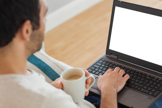 Digital png photo of biracial man with cup of coffee using laptop on transparent background - Powered by Adobe