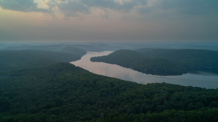 An aerial view of a boat curving around a lake in the country during sunset