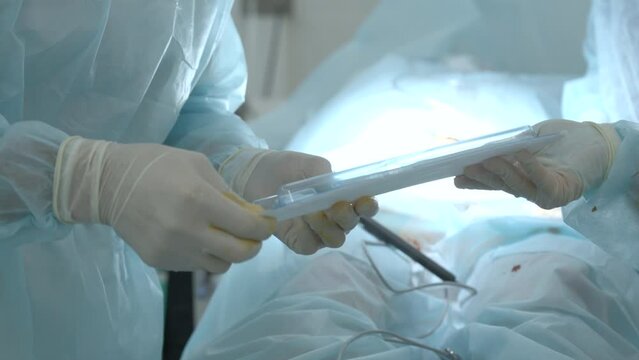 Nurse passing disposable sterile kit to a doctor in operating room. Action. Concept of healthcare and medicine.