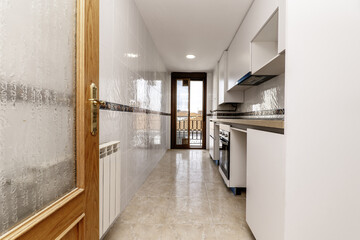 Room with an elongated kitchen with furniture on one side of the room, a wooden countertop and access to a terrace