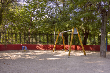 Fototapeta premium swing with chains on a playground with wooden arms and sand on the ground
