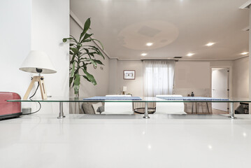 White wooden open kitchen counter with access to a living room with windows