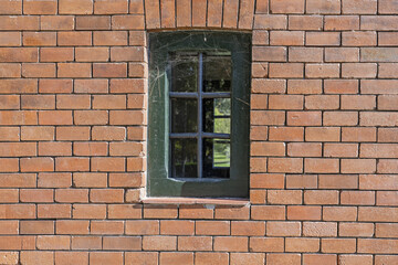 a small window with metal bars and cobwebs on a clay brick wall