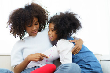 Lovely cute little girl gives mother her drawing post card in the international Mother's Day, American - African black ethnic family portrait. International Mother's Day concept.