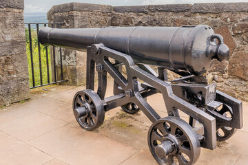 Cannon mounted on metal cart on rampart of castle.