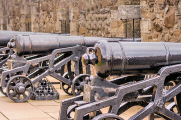 Cannon mounted on metal cart on rampart of castle.