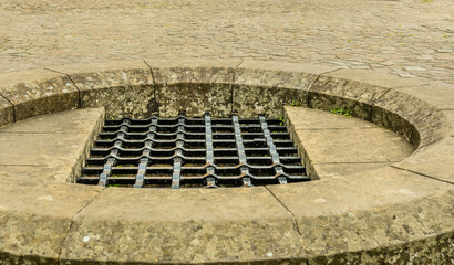 Metal grate over hole surrounded by concrete blocks.