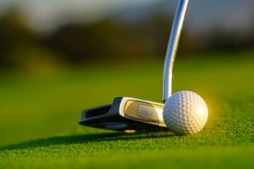 Golf ball and golf club on green in a beautiful golf course with morning sunshine.