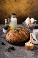 Freshly baked sourdough bread from whole grain flour and pumpkin seeds on a grid, olive oil and black olive on a rustic wooden table. Artisan bread.
