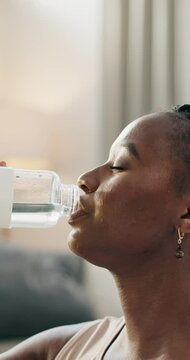 Thirsty, fitness and black woman drinking water in a house on a break from training or for clean diet. Healthy, sports and an African girl with a drink for nutrition, exercise or relax after workout
