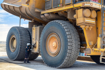 open pit diamond mine, worker at the fuel pump refuel huge truck with diesel - obrazy, fototapety, plakaty