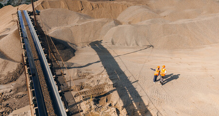 Team of industrial workers inspect sand quarry and check belt conveyor on open pit mine, industry banner