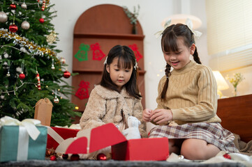 Two happy Asian girls are opening their Christmas gifts and celebrating Christmas together.