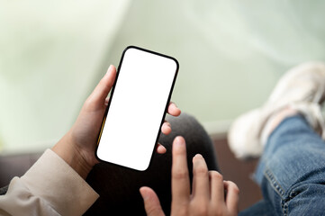 Close-up image a woman using her smartphone while sitting at a chair indoors.