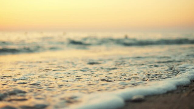 Beautiful sea waves and sand close up texture at tropical beach during golden sunset, high quality 4K slow motion travel vacation concept.