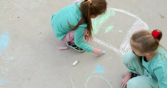 Happy children on sidewalk draw with chalk. Children art.