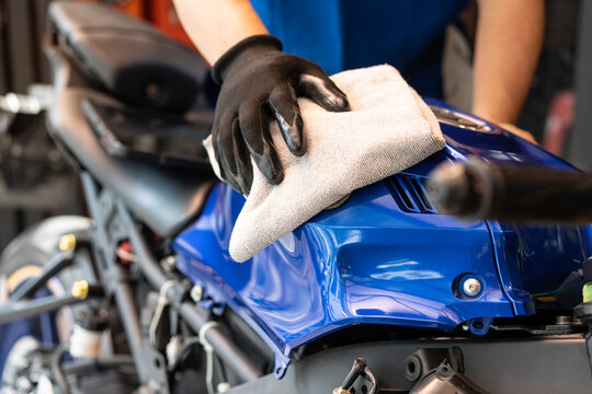 Biker man cleaning motorcycle , Polished and coating wax on fuel tank at garage. motorcycle maintenance and repair concept.