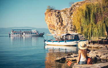 Macedonia- travel, tour tourism,vacation- Woman tourist enjoying Ohrid lake and famous traditional boats - obrazy, fototapety, plakaty
