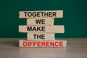 Brick blocks with red text TOGETHER WE MAKE THE DIFFERENCE. Beautiful green background, wooden...