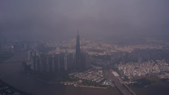 Aerial hyperlapse of Landmark building up in clouds, Vietnam. Drone travels in ccw direction around tower and panorama of skyline, Saigon River and traffic bridge. Symbol of Ho Chi Minh City, SE Asia.