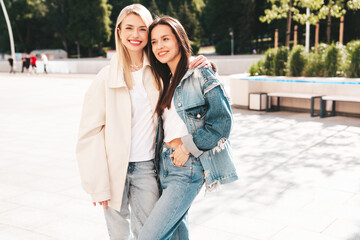 Two young beautiful smiling hipster female in trendy summer clothes. Carefree women posing in the street. Positive models having fun outdoors at sunny day. Cheerful and happy