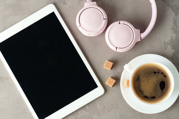 Digital tablet and coffee cup on gray background close up