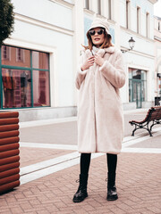 Young beautiful smiling lady wearing trendy white faux fur coat. Stylish woman posing in the street...