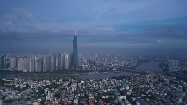 Aerial orbit of Landmark building Vietnam in early morning. Drone travels in ccw direction around skyscraper and panorama of skyline and Saigon River. Symbol of Ho Chi Minh City and SE Asia.