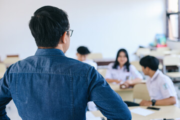Angry teacher looking at students talking during lessons in classroom