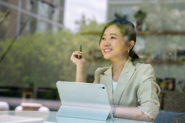 Fototapeta premium Asian woman sitting and working in a coffee shop
