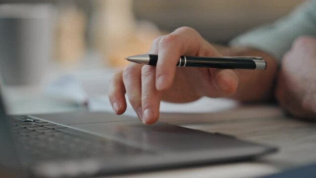 Man hands writing in notebook at desk close up. Man working online using laptop.