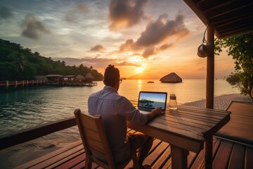 Young nomad man sitting on a Beach, working on the internet remotely at sunset, Traveling with a computer.