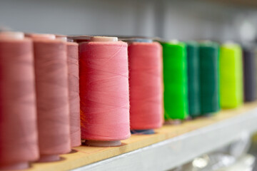 Row of multicolored thread spools at sewing factory