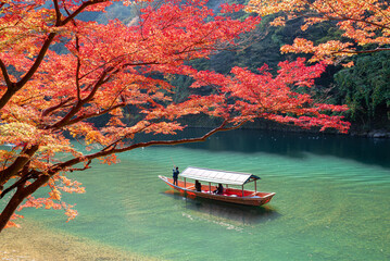  Boatman punting the boat for tourists to enjoy the autumn view along the bank of Hozu river in Arashiyama Kyoto, Japan.