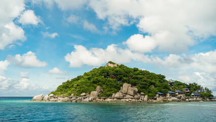 Fototapeta premium Scenic view tropical paradise with peaceful resort, rocky coastline, clear turquoise sea with coral reef against cloud sky. Koh Nangyuan Near Koh Tao Island, Thailand.
