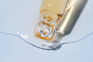 Bottle pipette dropper close up and Liquid yellow-orange retinol or vitamin c gel or serum on a blue background