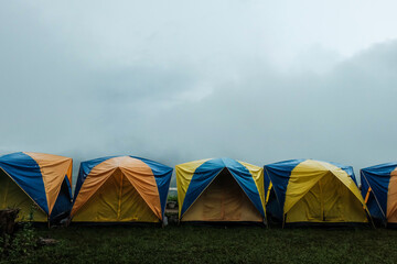 Tent in camping with flog and mountain view. Tent on campsite by the hill in rainy day. Tent wet after rain. Water droplets on the tent. Khao Kho, Phetchabun Province in Thailand. - obrazy, fototapety, plakaty