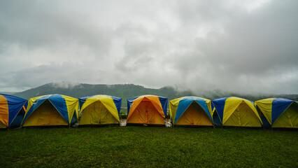Tent in camping with flog and mountain view. Tent on campsite by the hill in rainy day. Tent wet after rain. Water droplets on the tent. Khao Kho, Phetchabun Province in Thailand.