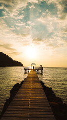 The wooden bridge on the sea in summer. The wooden bridge on sea at sunset, Thailand. Wooden bridge in the port over sea between sunset. Koh Kood Island, Trad Province, Thailand